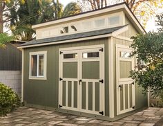 a small green and white shed sitting in the middle of a yard