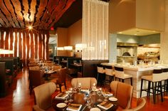 an empty restaurant with tables and chairs set up for formal dining, in front of the kitchen