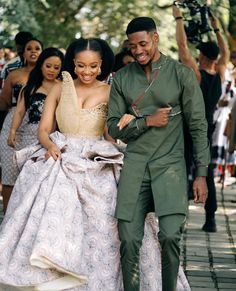 a man and woman are walking down the street in formal attire with cameras around them