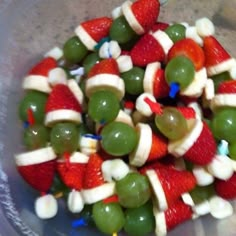 a plastic bowl filled with fruit and veggies covered in santa's hats