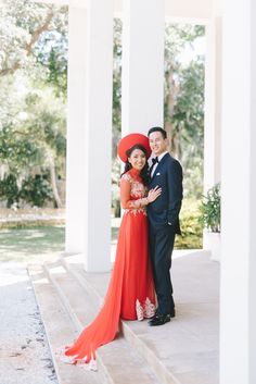 a man and woman standing next to each other in front of white pillars with columns