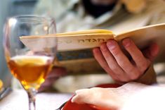 a person is reading a book at a table with wine glasses and bread in front of them