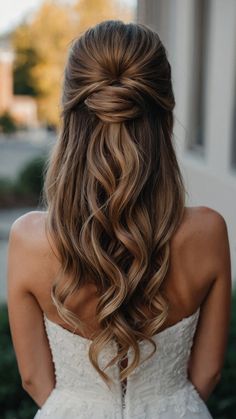 the back of a woman's head with long, wavy hair in her wedding dress