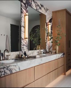 a bathroom with marble counter tops and two sinks in front of large mirrors on the wall