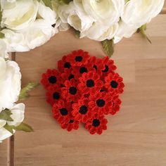 a crocheted red and black ladybug brooch sits next to white flowers