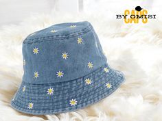 a blue hat with daisies on it sitting on top of a white fur rug