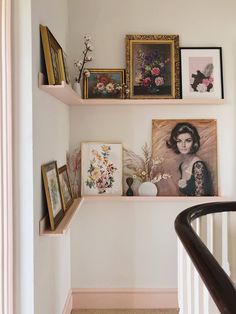 a staircase with pictures and other items on the wall above it, along with framed photos