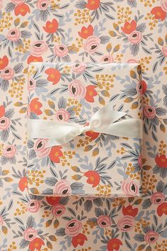 two wrapped presents are sitting on a floral wallpaper