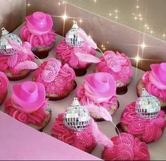 cupcakes with pink frosting and decorations in a box