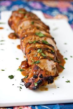 a white plate topped with meat covered in sauce and garnished with parsley