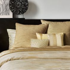 a bed with gold sheets and pillows on top of it