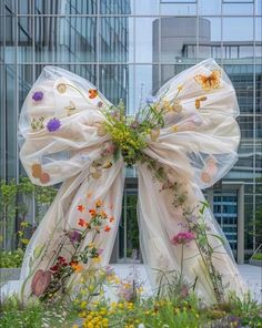 a bow made out of sheer fabric with flowers on it in front of a building