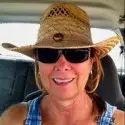 a woman sitting in the back seat of a car wearing a straw hat and sunglasses