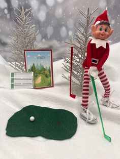 an elf is playing golf in the snow next to some cards and a green marker