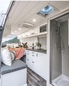 the interior of a camper with a dog sitting on the bed and shower area