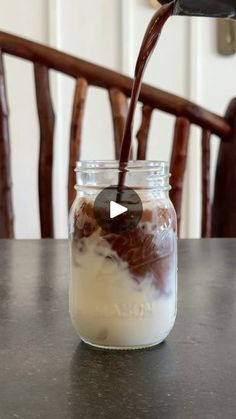 a glass jar filled with food sitting on top of a table next to a wooden chair