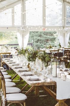 a long table with white linens and greenery is set up for an outdoor event