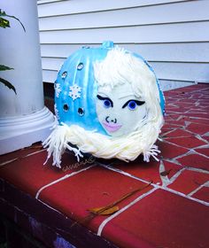 a blue and white mask sitting on top of a red brick floor next to a house