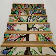 an artistic stair case painted with colorful leaves and tree design on the bottom, along with wooden handrails