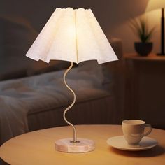 a table with a lamp on top of it next to a cup and saucer