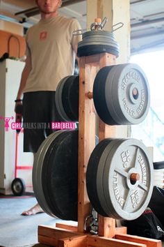 a man sitting on the ground in front of a gym machine with two large wheels attached to it