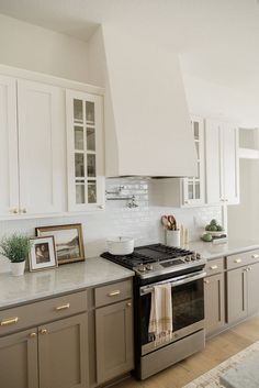 a kitchen with white cabinets and stainless steel stove top oven in the middle of it