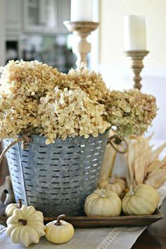 a basket filled with lots of flowers sitting on top of a table next to candles