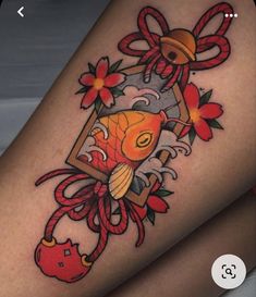 a woman's thigh with a fish and flowers tattoo design on the side of her leg