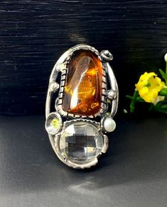 Baltic Amber with Quartz ring in sterling silver Hand-made Sterling Silver 925, size 8 Stones used: Unique Baltic Amber, Quartz, Peridot, Pearl Face of the ring: Height - 40mm, Width-25mm, Band height-8-5mm Unique Handcrafted One-of a-kind Design Ring Each Piece of Jewelry in my Collection is Absolutely One of a Kind! When you start wearing a piece of my jewelry you will fall in love with it more and more each day and feel that good Energy and Love that I pass into it while creating this piece o Unique Amber Sterling Silver Rings, Unique Multi-stone Citrine Rings, Unique Amber Ring Jewelry, Unique Amber Ring, Silver Citrine Rings For Jewelry Making, Artisan Amber Ring Jewelry, Artisan Sterling Silver Rings With Unique Variations, Unique Citrine Rings With Polished Finish, Unique Citrine Ring With Polished Finish