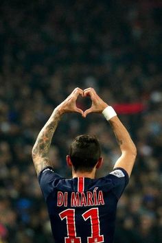 a man with his hands in the shape of a heart at a soccer game,