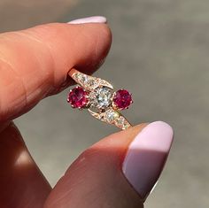 a close up of a person holding a ring with three stones on the top and bottom