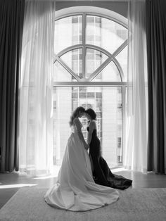 black and white photograph of two brides sitting on the floor in front of a window