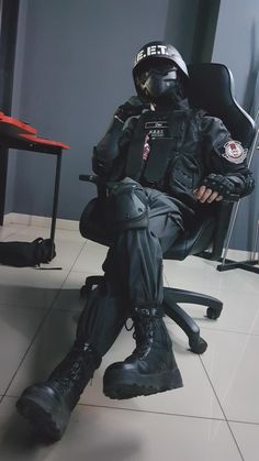 a man sitting in an office chair with his feet on the desk and wearing black boots