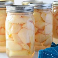 four jars filled with sliced apples on top of a table