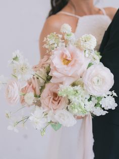 a bride and groom holding a bouquet of flowers