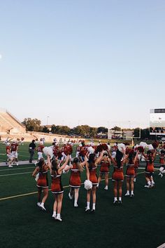 a group of cheerleaders standing on top of a field