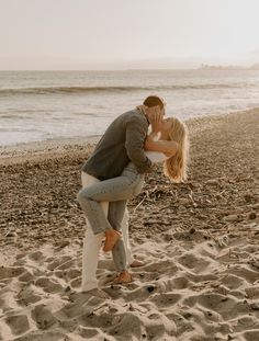 a man and woman kissing on the beach