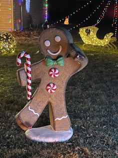 a gingerbread man statue with candy canes in front of christmas lights on the lawn