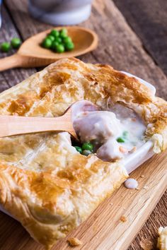 a wooden cutting board topped with meat and veggies covered in gravy