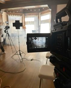 a camera set up on a tripod in a room with wood floors and windows