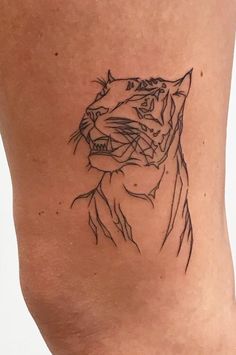 a black and white photo of a tiger tattoo on the side of a woman's leg