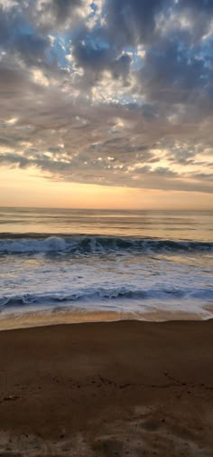 the sun is setting over the ocean with waves coming in