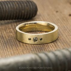 a close up of a gold ring on a wooden surface with an object in the background