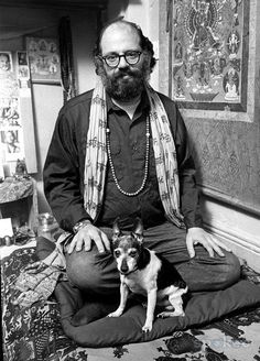 a man sitting on top of a bed with a dog in front of him and looking at the camera