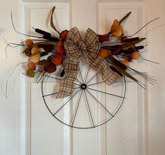 a wreath with dried flowers and leaves hanging on a door