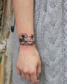 a person's wrist with a tattoo on it and palm trees in the background