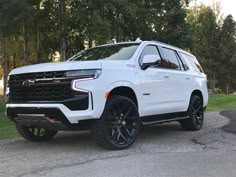 a white truck parked on the side of a road next to some grass and trees