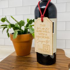 a bottle of wine sitting on top of a wooden table next to a potted plant