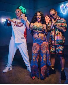 two men and a woman posing in front of neon lights