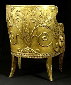 an ornately carved gold bowl on stand against a black background in the shape of a plant